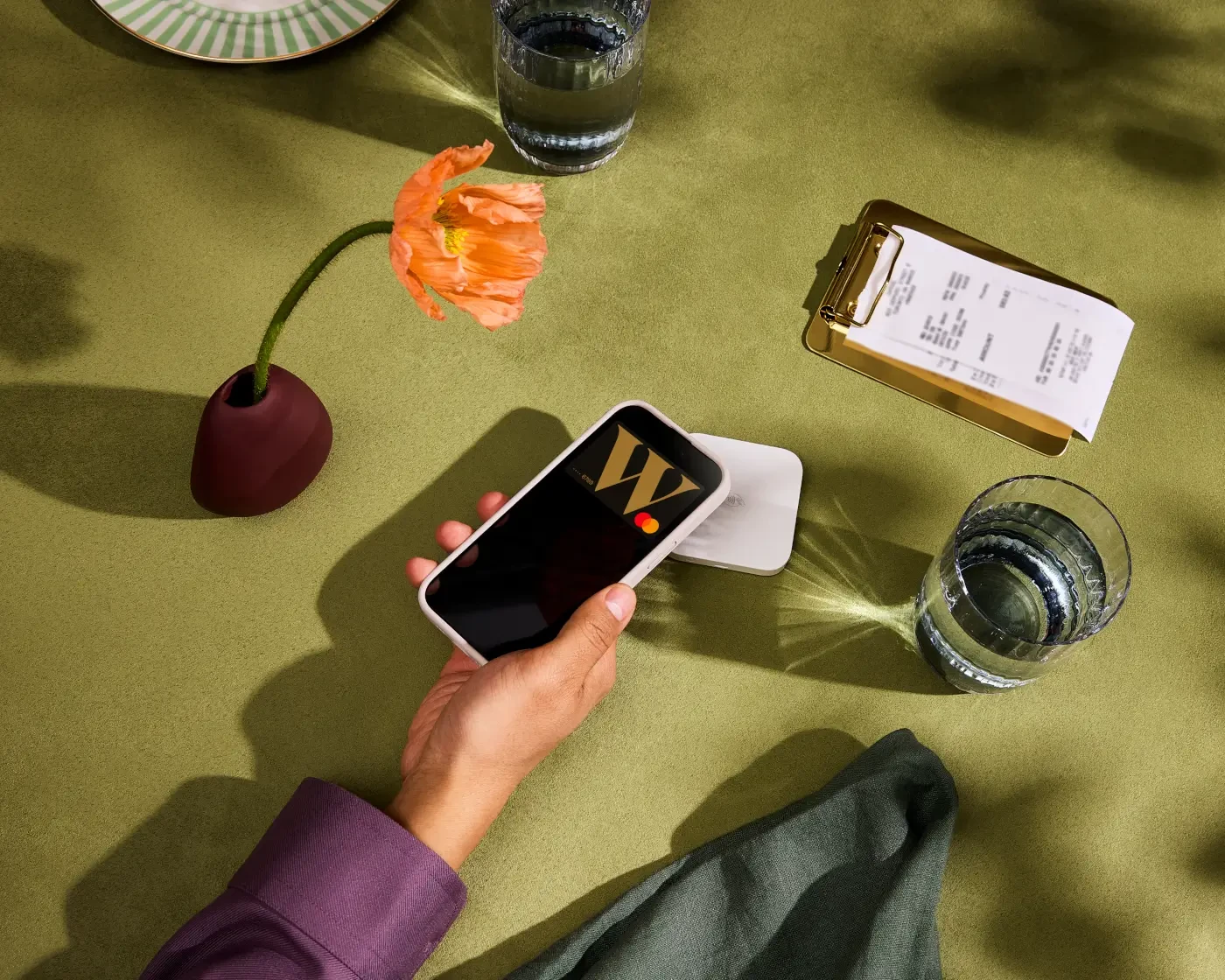 Photograph of someone tapping their Wealthsimple Cash card from their digital wallet in a restaurant setting.