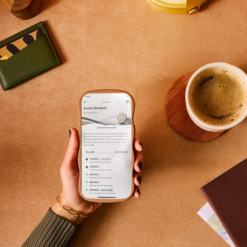 Une personne qui tient un téléphone montrant l'expérience sur l'appli Wealthsimple.