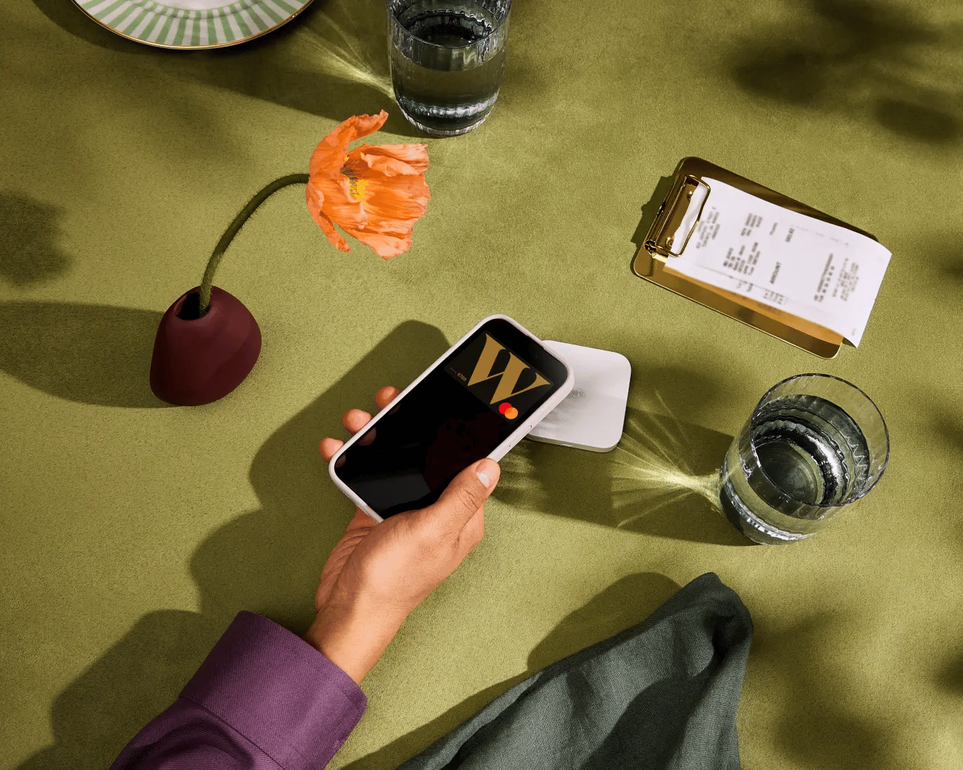 Photograph of someone tapping their Wealthsimple Cash card from their digital wallet in a restaurant setting.