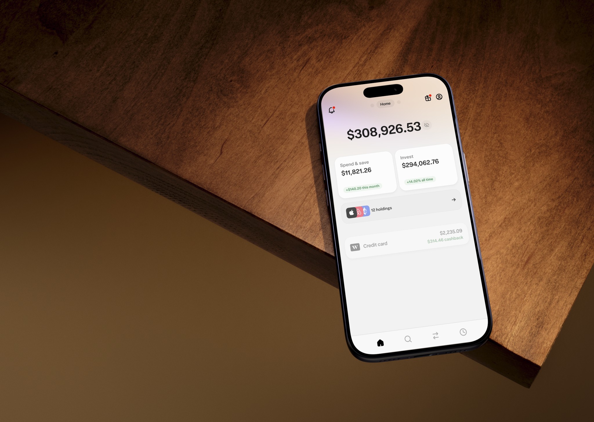 An iPhone on the edge of the table, displaying the home screen of Wealthsimple's app.