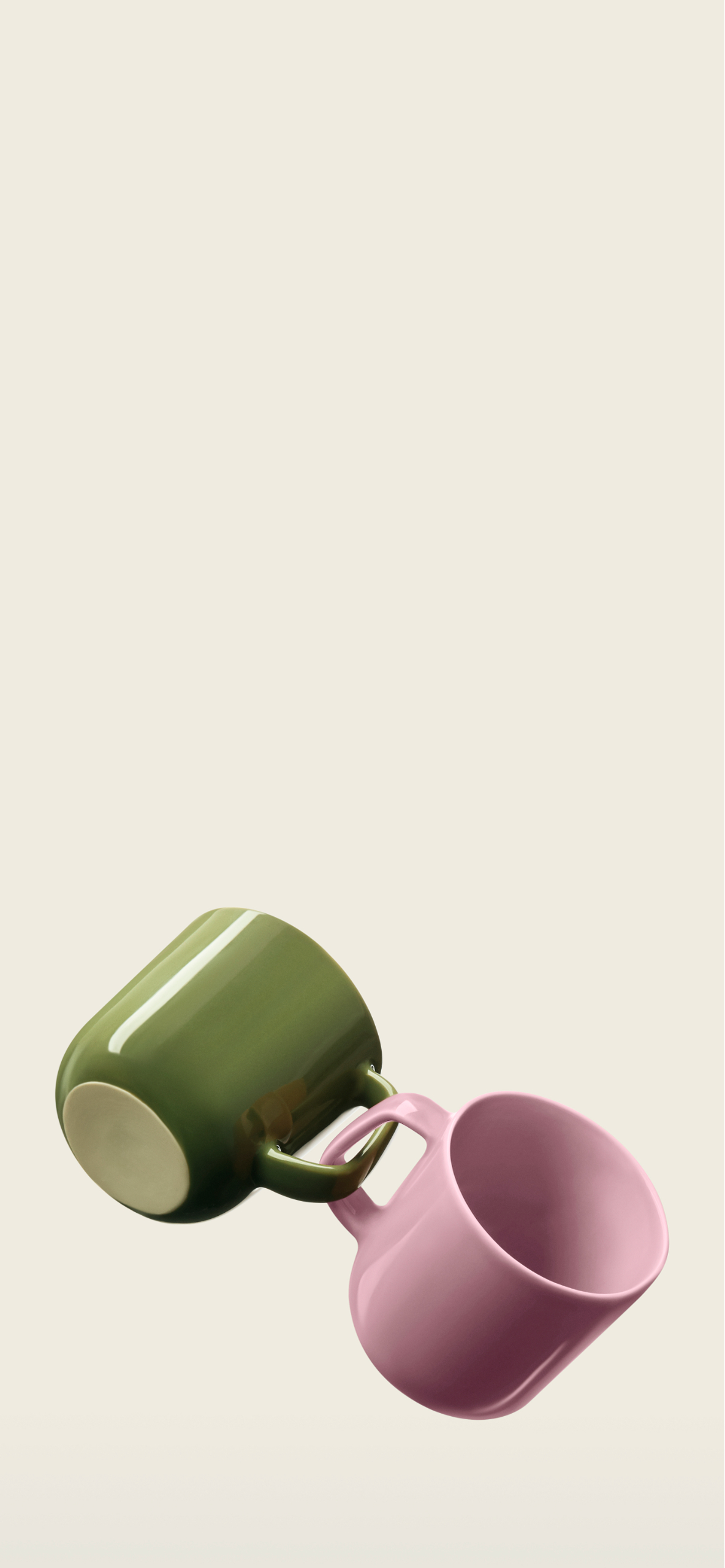 Une tasse verte et une tasse rose, reliées par leurs anses.