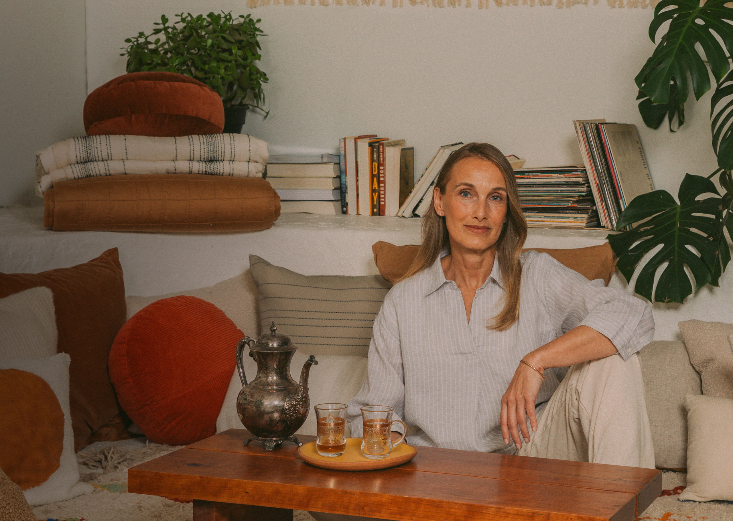 A woman sits in a cozy, book-filled living room, representing a Wealthsimple Wealth Management client.