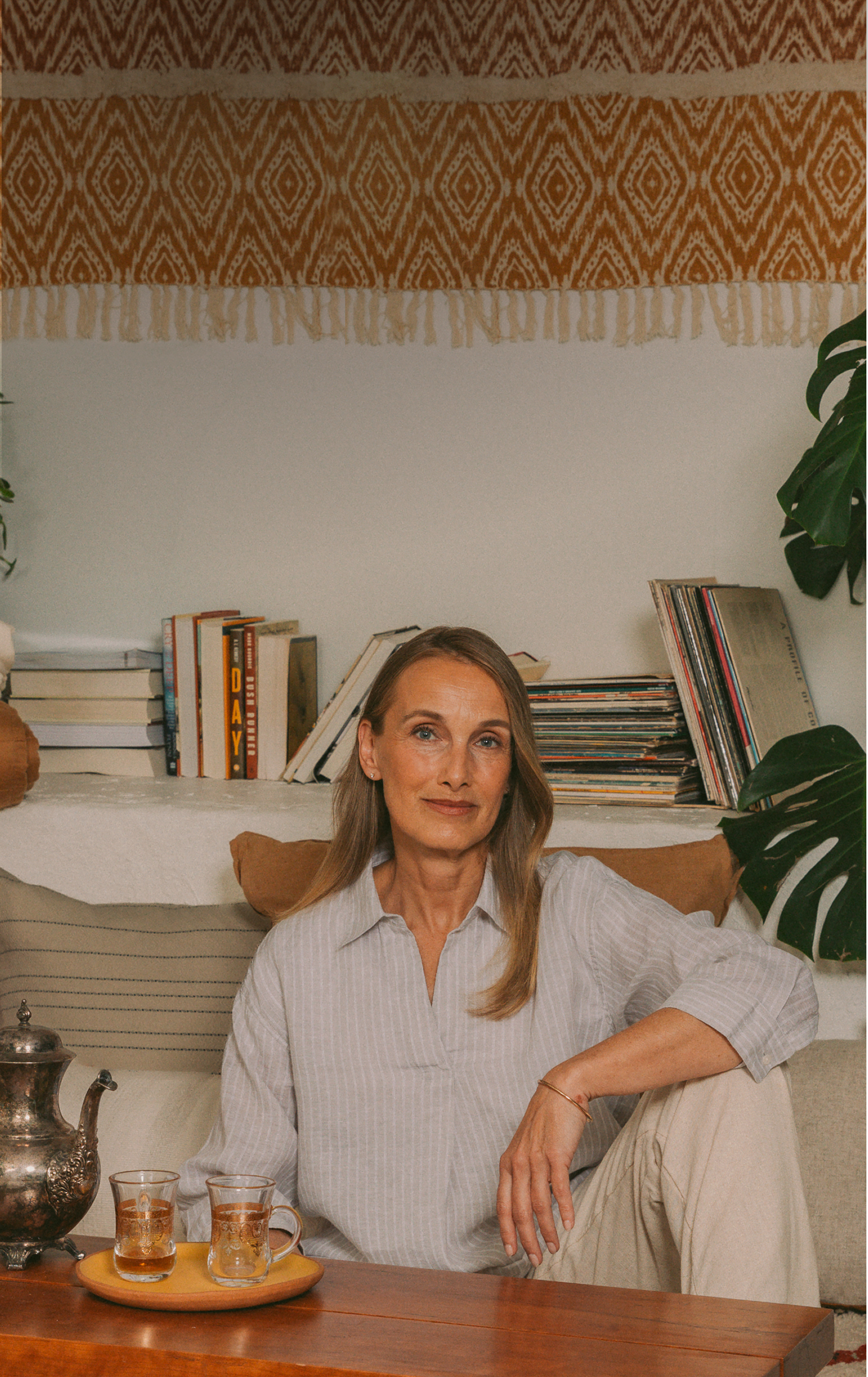 A woman sits in a cozy, book-filled living room, representing a Wealthsimple Wealth Management client.
