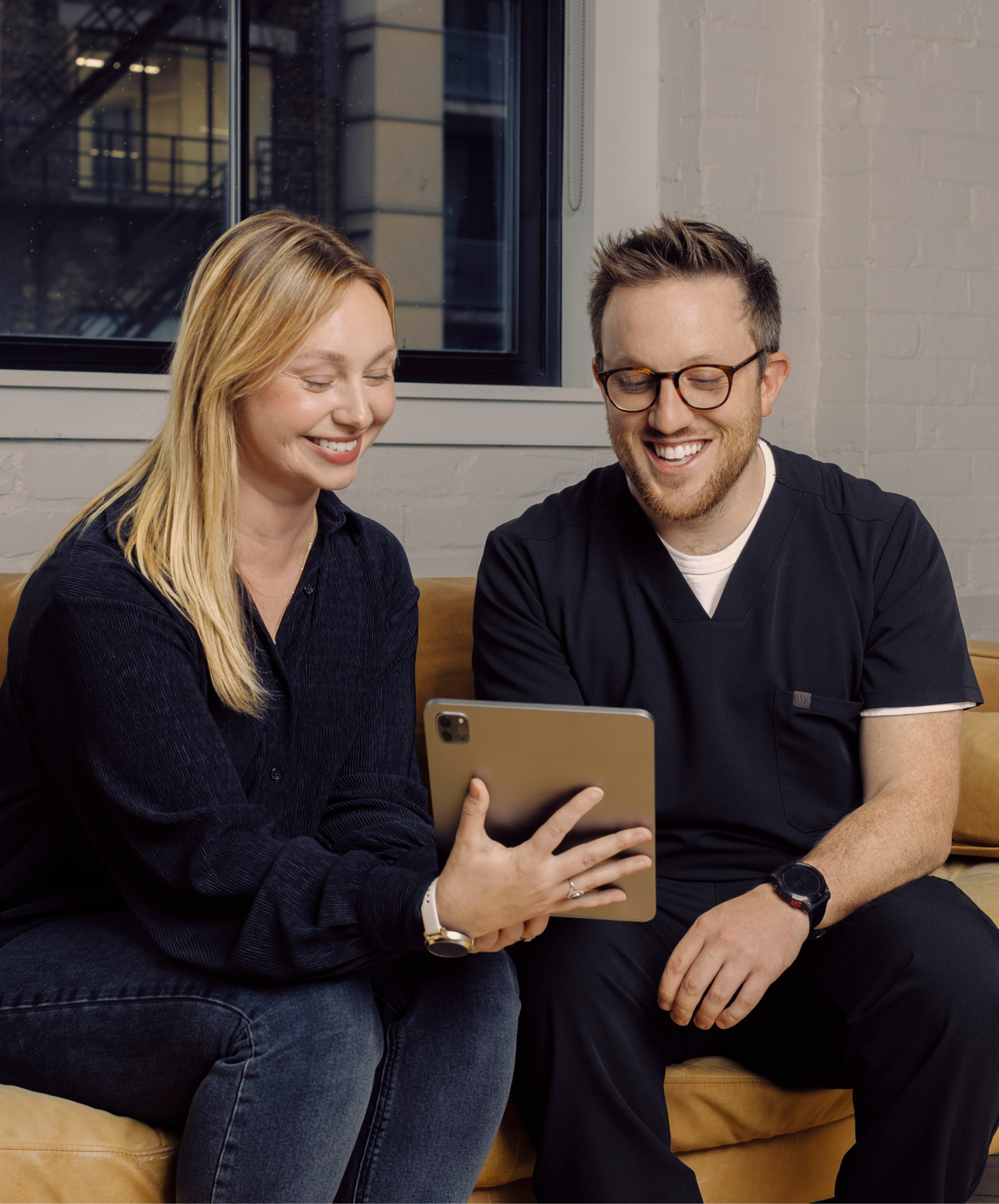 A woman shows an iPad to a physician in Wealthsimple scrubs.